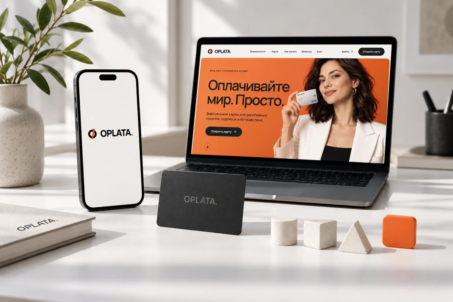 Сайт OPLATA на ноутбуке рядом с телефоном и брендированными предметами